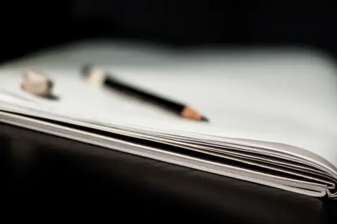 Otwarta książka z ołówkiem i gumką do ścierania.